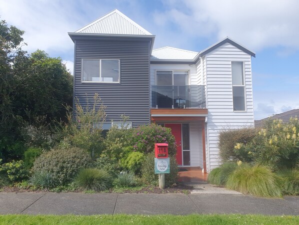 A two-story house with a red door, a balcony, and a mailbox. - 11A Seaview.
Ocean and Otway Ranges views. Close to beach. Pet friendly. (Apollo Bay)