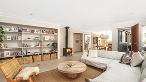 Ein modernes Wohnzimmer mit Kamin, Bücherregalen, einer Couch und einem Essbereich.