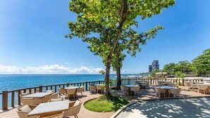 Un espace extérieur aménagé avec des tables et des chaises, offrant une vue sur l’océan.