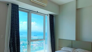 Une chambre d’hôtel avec une grande fenêtre, un lit et un appareil de climatisation.