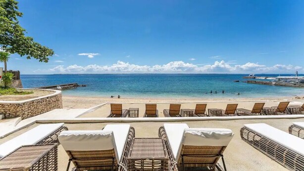 Une vue sur la plage avec des chaises longues et un mur de pierre.