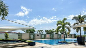 Un espace piscine comprenant plusieurs bassins, des palmiers et un ciel dégagé.