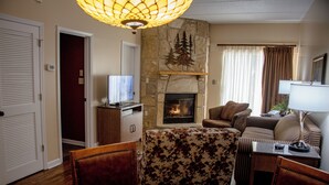 Ein Wohnzimmer mit Kamin aus Stein, einem Fernseher, einer Couch und einem Essbereich mit Tisch und Stühlen.