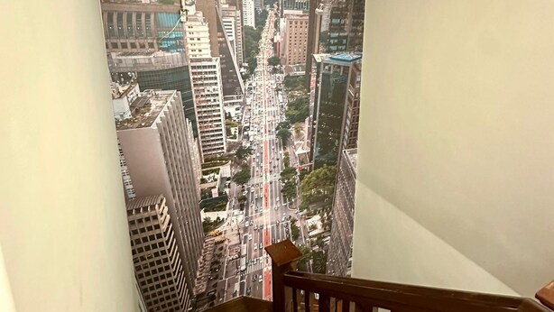 A staircase with a view of a cityscape through a window. - Hostel Distrito 011 (São Paulo)