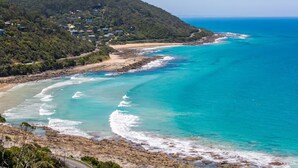 A coastal landscape with a beach, ocean waves, and a forested hill. - Arguably the best views in Wye River (Wye River)