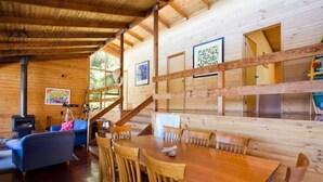 A wooden cabin interior with a dining table, chairs, a sofa, and a staircase. - Arguably the best views in Wye River (Wye River)