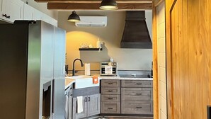 A kitchen with wooden beams, pendant lights, a refrigerator, a stove, and a sink.