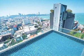 Ein Hochhaus mit Pool auf dem Dach mit Blick auf eine Skyline und das Meer.