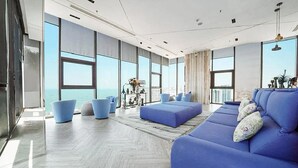 Een moderne woonkamer met grote ramen, een blauwe bank en een salontafel.