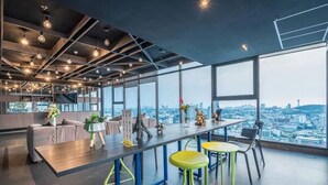 Een modern interieur met een lange tafel, barstoelen en uitzicht op de stad door grote ramen.