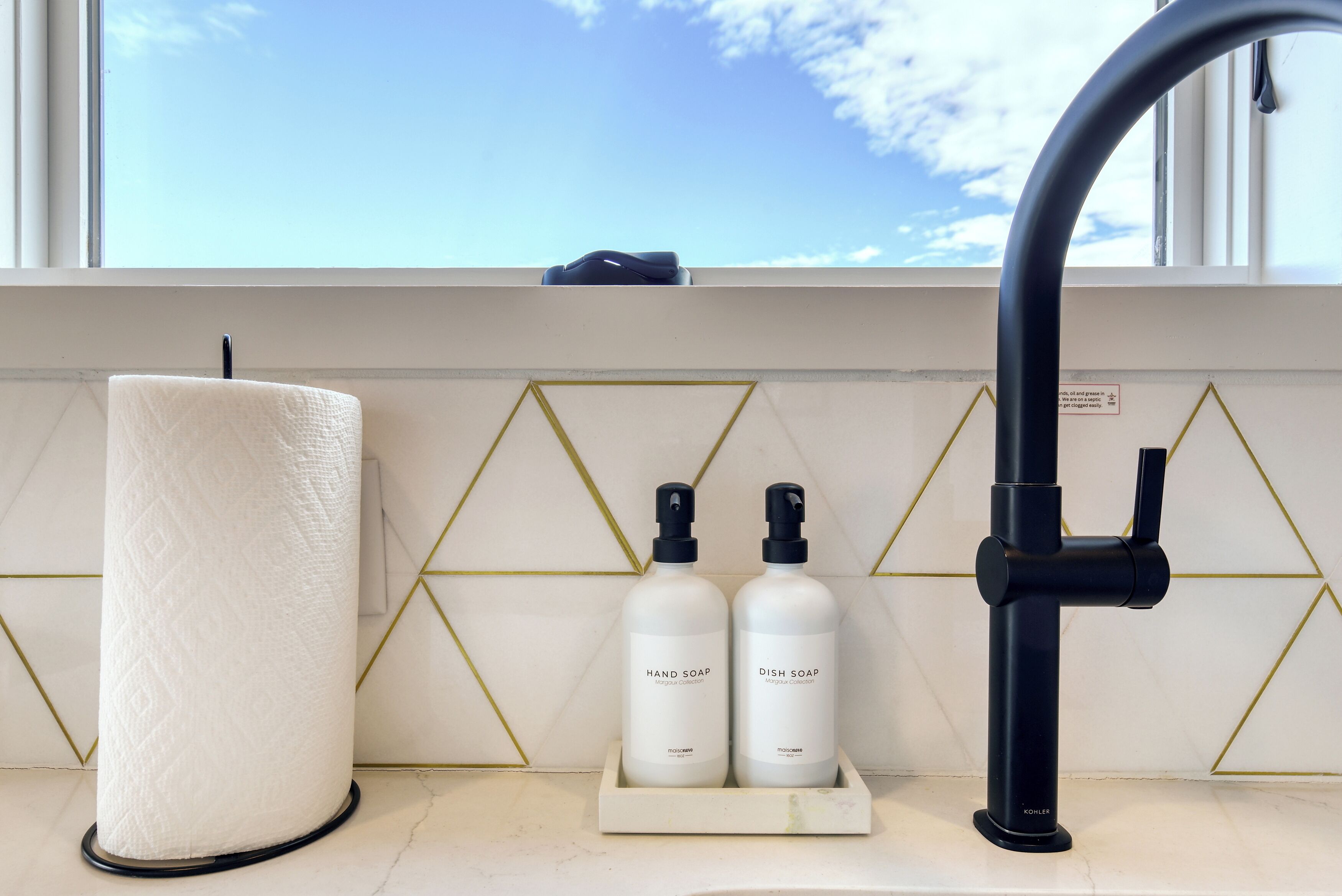 Un baño con un lavabo de mármol, dos botellas de jabón y una toalla.