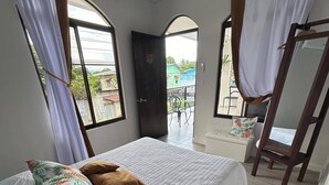 Une chambre à coucher avec un lit, des oreillers, une fenêtre et une porte donnant sur un balcon.