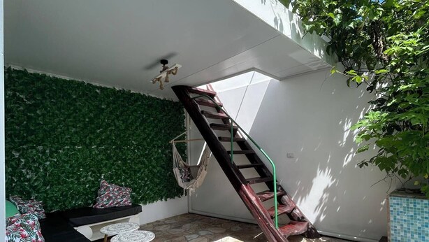 Une terrasse extérieure moderne avec un sol en pierre, un hamac, un escalier et une piscine.