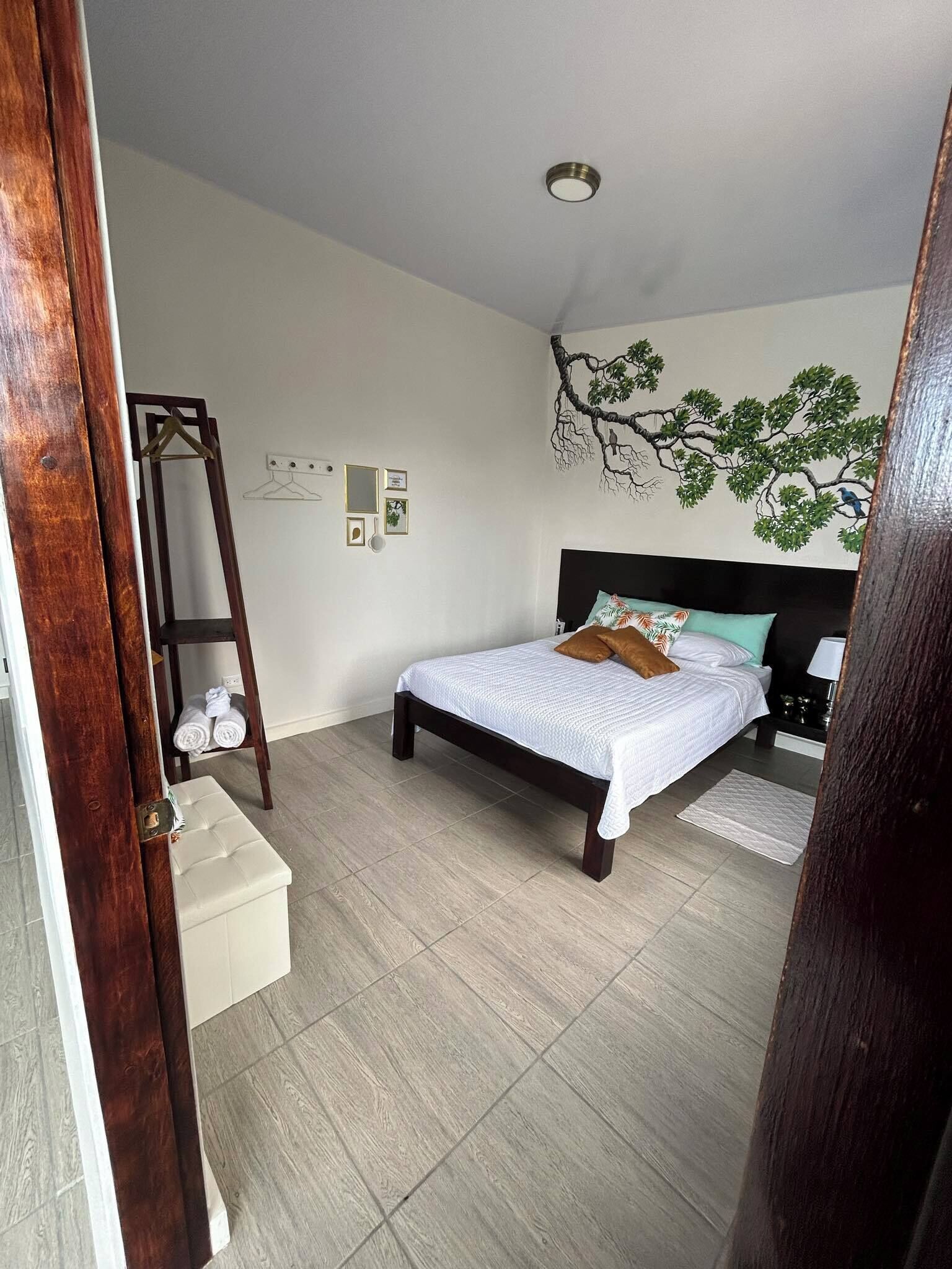 Une chambre à coucher comprenant un lit, une commode, une étagère fixée au mur et un luminaire au plafond.