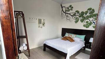 Un dormitorio con cama, cómoda, estante en la pared y luz en el techo.