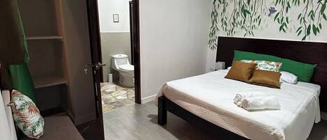 Un dormitorio con cama, armario, baño y una escalera.