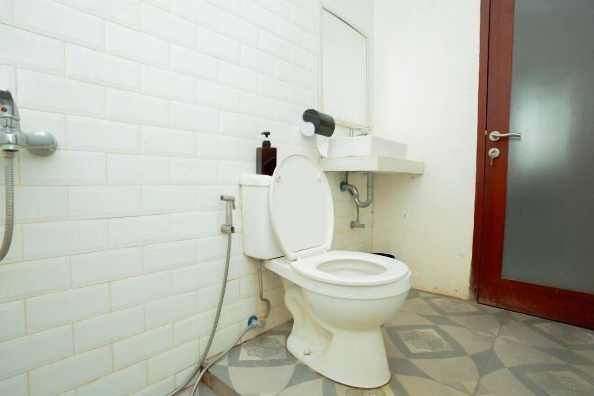 A bathroom with a white toilet, a shower, and a sink.