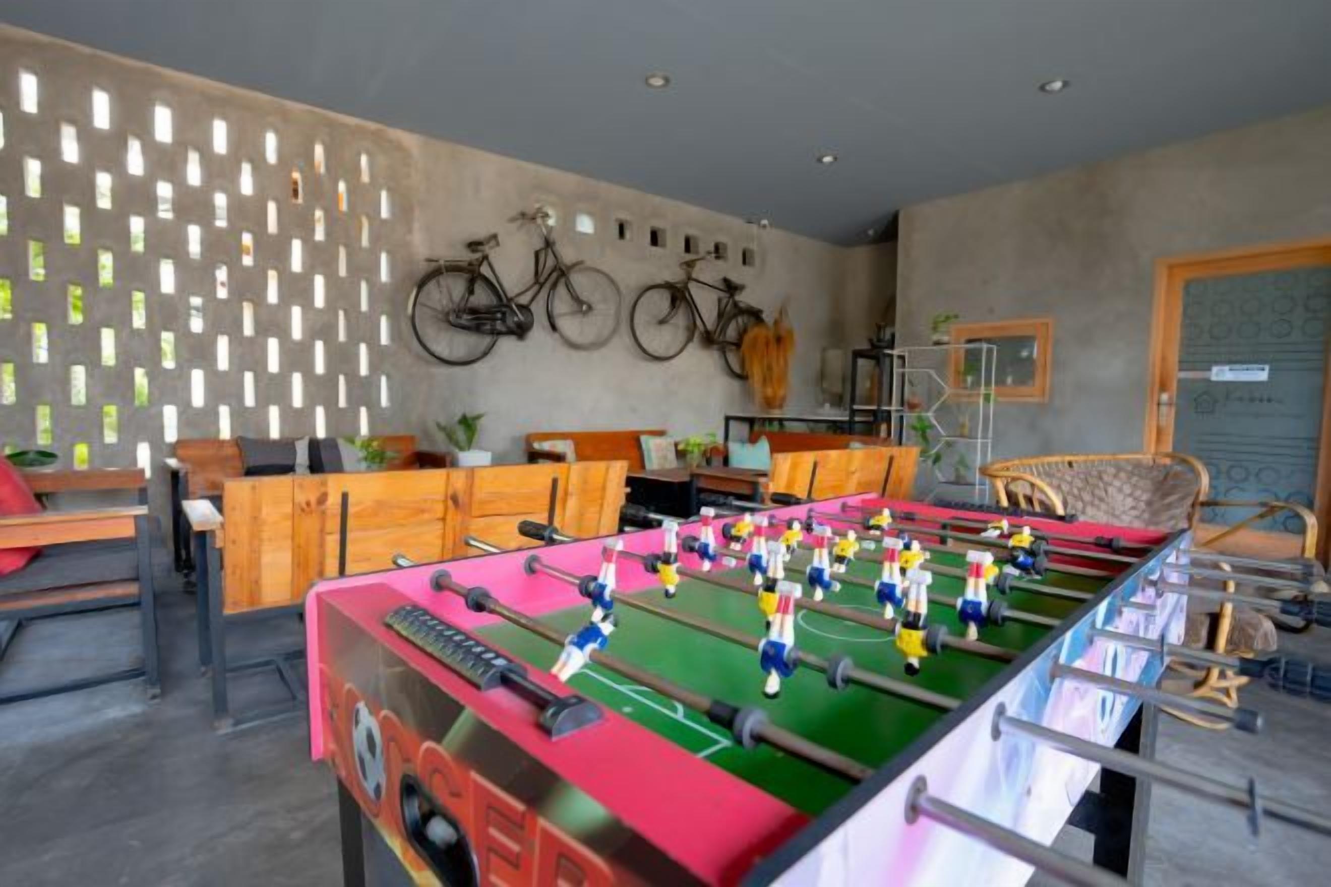 A room with a foosball table, bicycles mounted on the wall, and a billiards table.