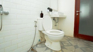 Un baño pequeño y limpio con azulejos blancos, un inodoro blanco, un secador de manos y un dispensador de jabón.