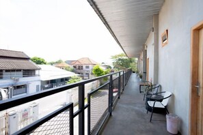 Un balcon avec une balustrade en métal, une table et deux chaises.
