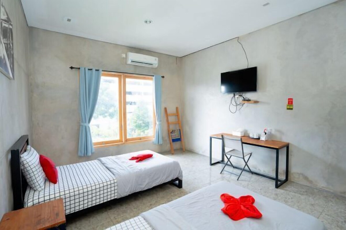 A room with two beds, a desk, a TV, and an air conditioning unit.