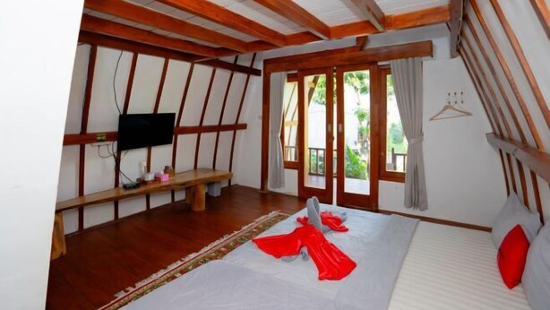 Un dormitorio con cama, un banco, un televisor y vistas al exterior.