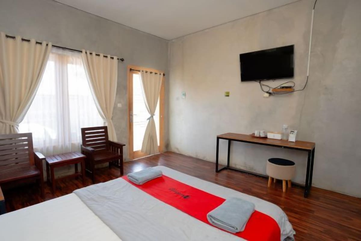 A hotel room with a bed, a desk, a chair, a television, and curtains.