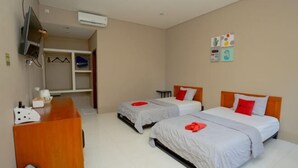 Habitación de hotel con dos camas, un escritorio, un televisor y un equipo de aire acondicionado.