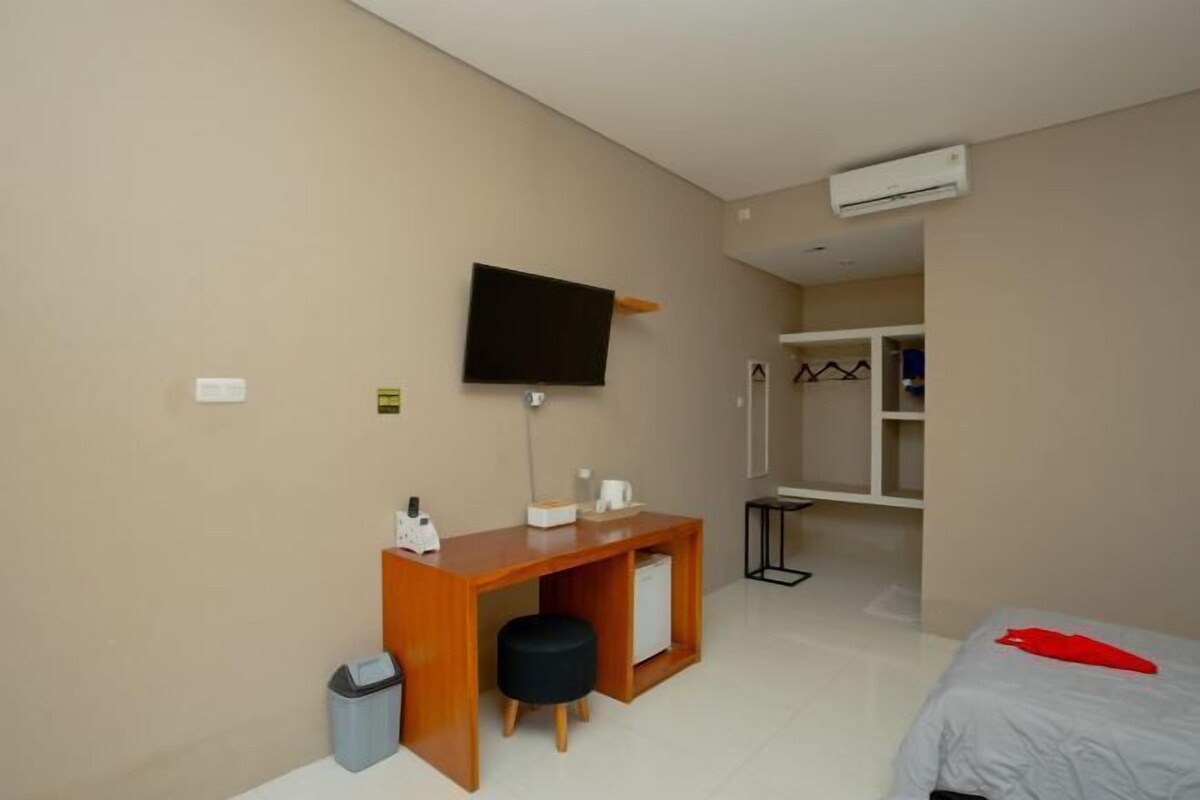 A hotel room with a bed, a desk with a chair, a television, and a wardrobe.