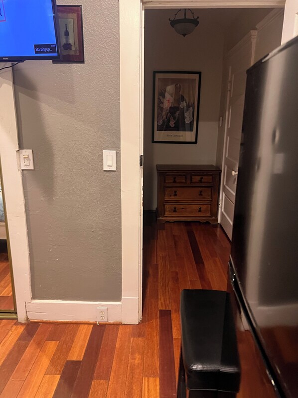 A kitchen with a refrigerator, a bench, wooden cabinets, and a painting on the wall.