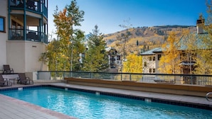 Piscina con vistas a un paisaje montañoso y árboles de colores otoñales.