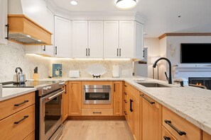 A modern kitchen with white cabinetry, stainless steel appliances, and a marble countertop. - Beaver Creek Residences 2 Bedroom Luxury Vacation Rental (Avon)