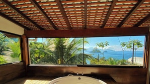 A hot tub under a wooden ceiling with a view of the ocean and palm trees. - Casa Varandas (Ubatuba)