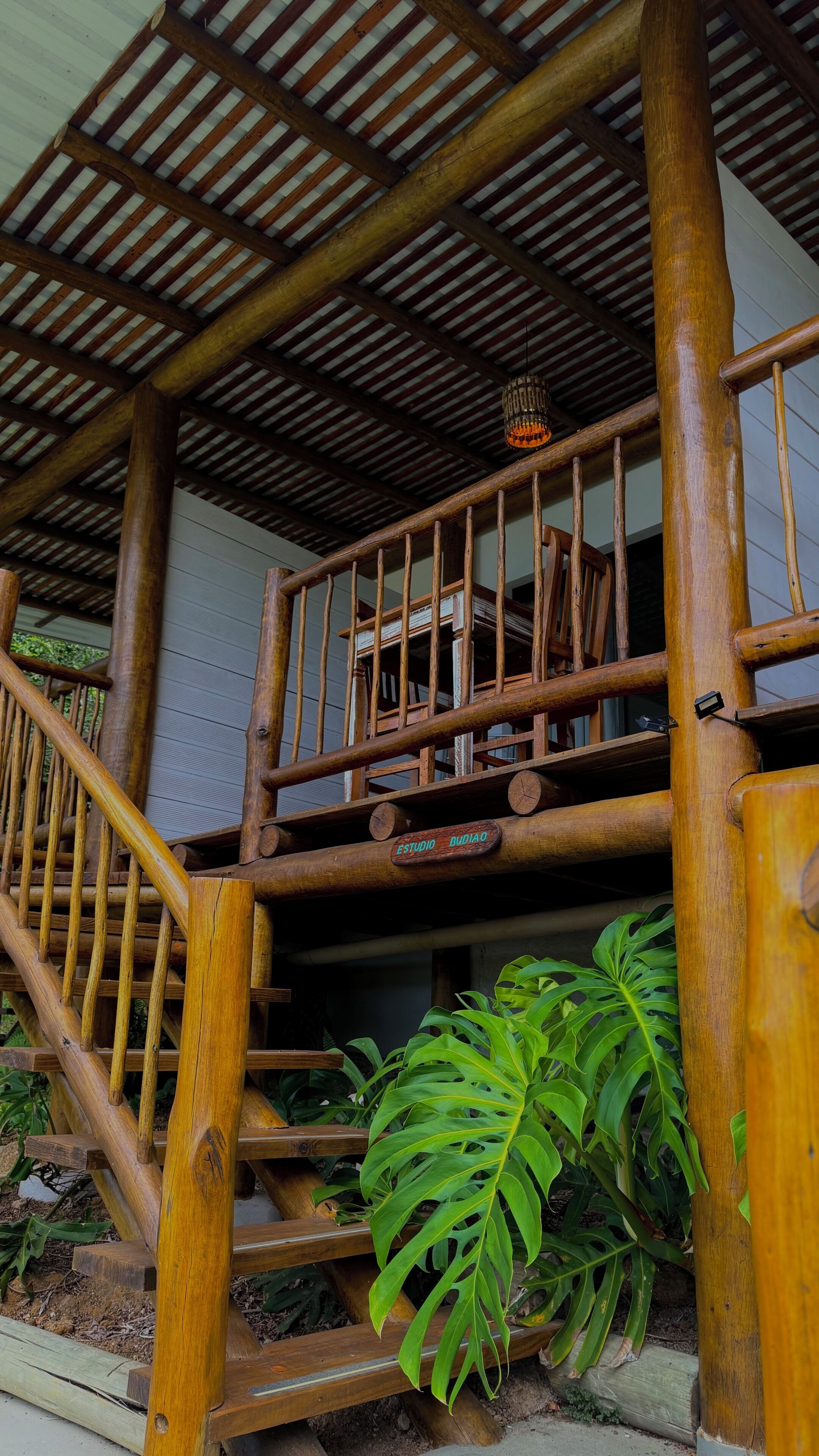 Un escalier en bois avec une main courante, une balustrade en bois et une enseigne sur laquelle on peut lire « ESTUDIO RUIDO ».