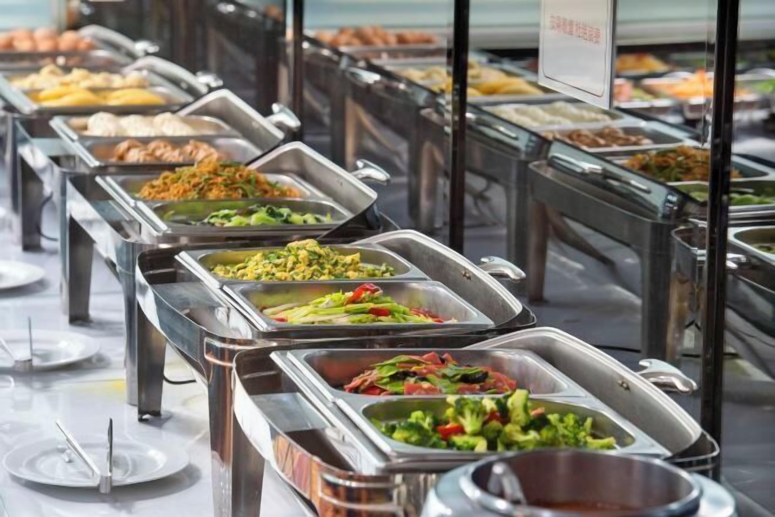 Buffet com diversas opções de comida em bandejas de metal.