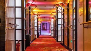 A hotel corridor with a red carpet, multiple doors, and a fire extinguisher. - AutobotsOutbots Hotel (Aquarium Station) (Zhengzhou)