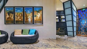 A lobby with a sofa, a chair, and a bookshelf. - AutobotsOutbots Hotel (Aquarium Station) (Zhengzhou)