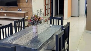 Une cuisine moderne dotée d’un téléviseur encastré, d’un coin repas avec une table en verre et d’un réfrigérateur.