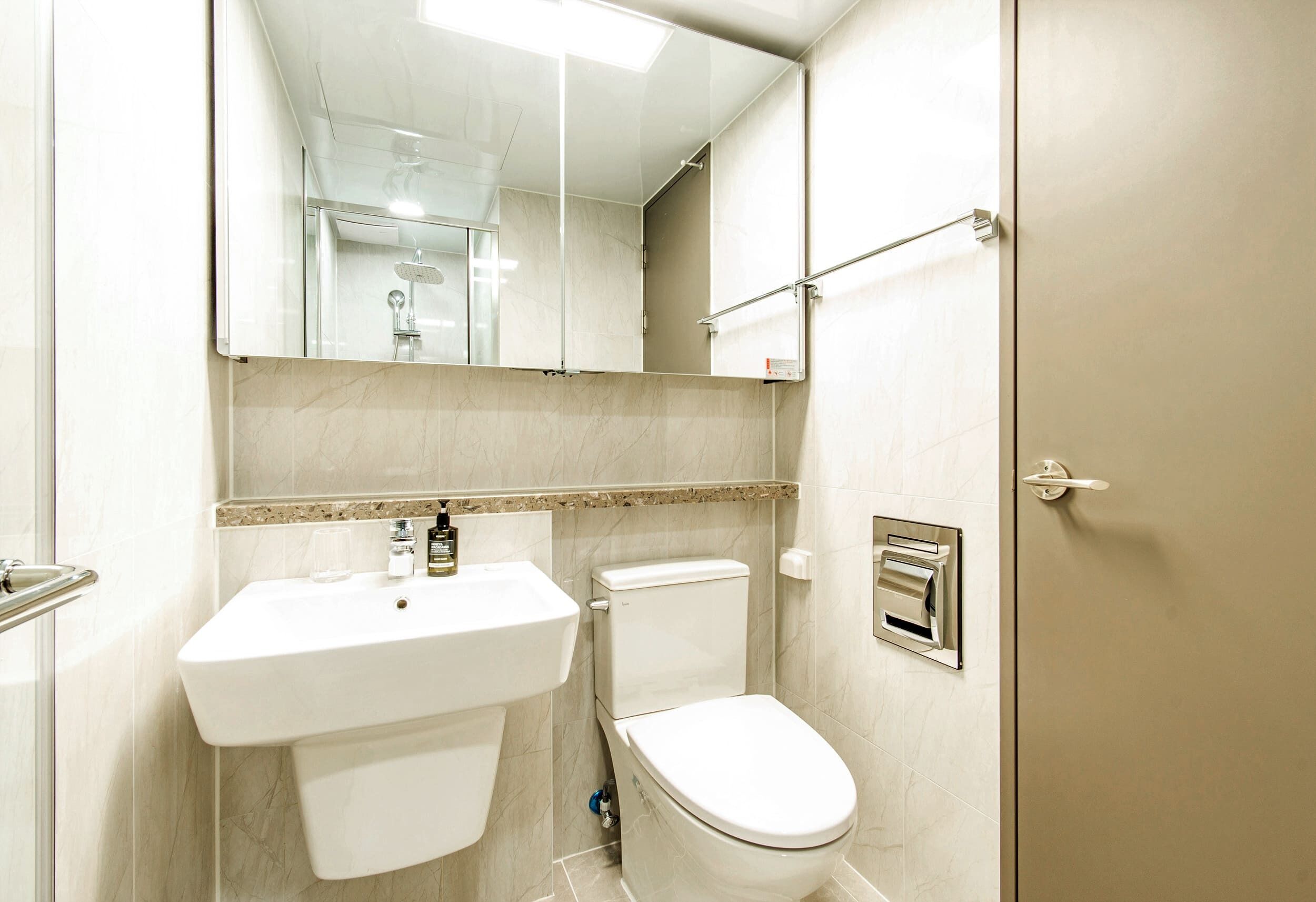 Ein modernes Badezimmer mit Waschbecken, Toilette und einer Duschkabine aus Glas.