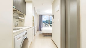 A hotel room with a washing machine, a bed, a balcony with a view of the city, and a large window. - Ariari Hotel (Jeongseon)