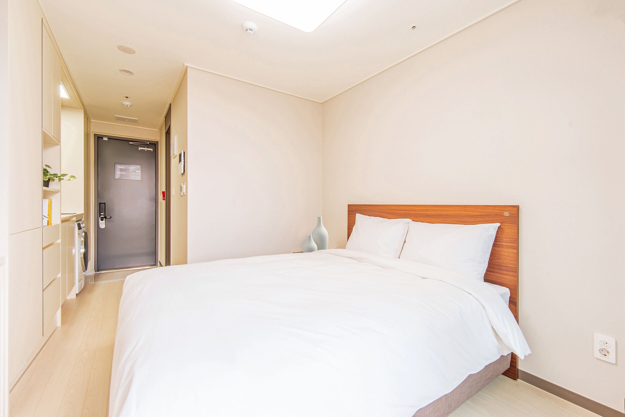 Una habitación de hotel con una cama grande, un cabecero de madera, una mesita de noche y otra mesita auxiliar.