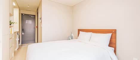 A hotel room with a large bed, a wooden headboard, a bedside table, and a nightstand.