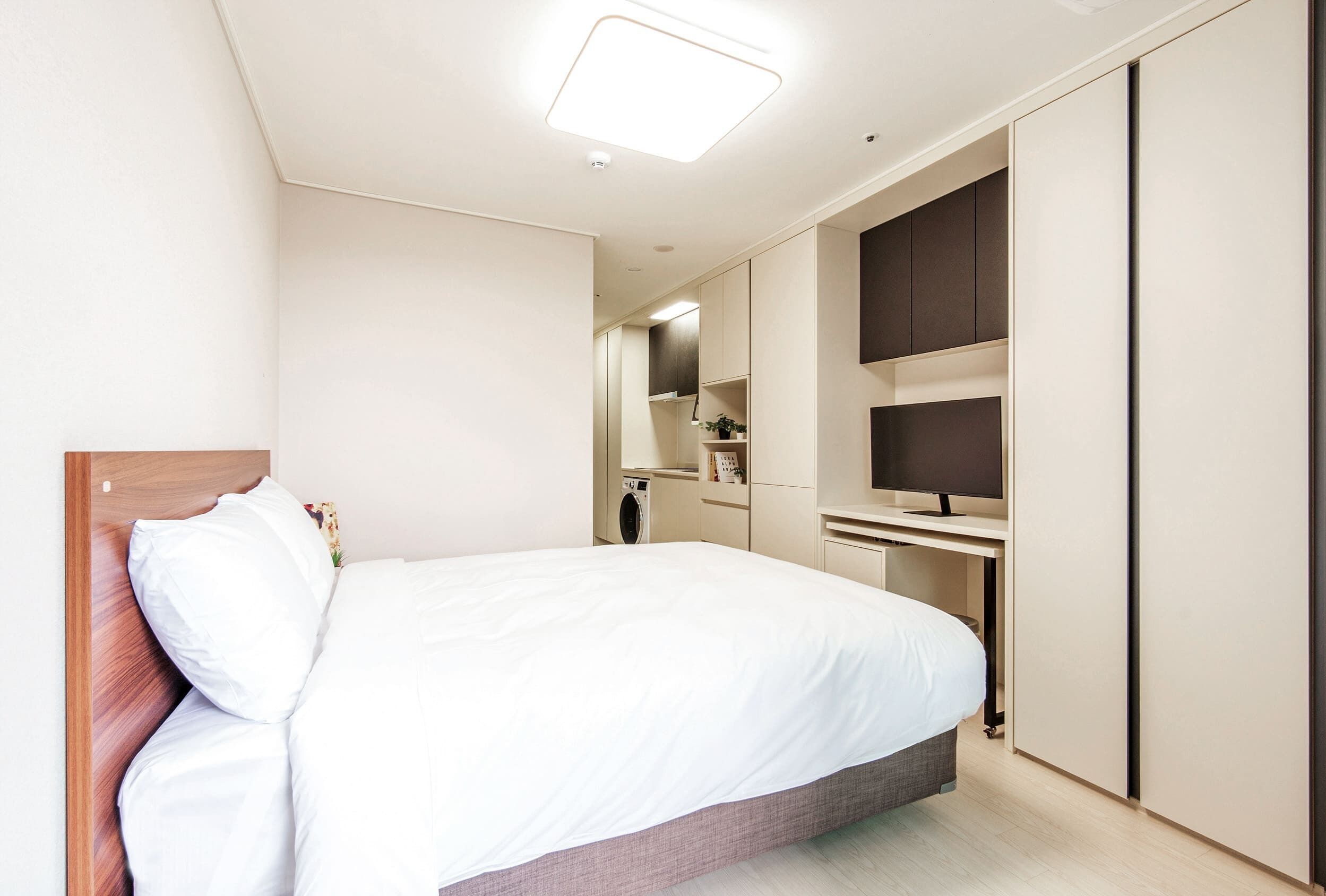 Una habitación de hotel moderna con una cama, un escritorio y un televisor.