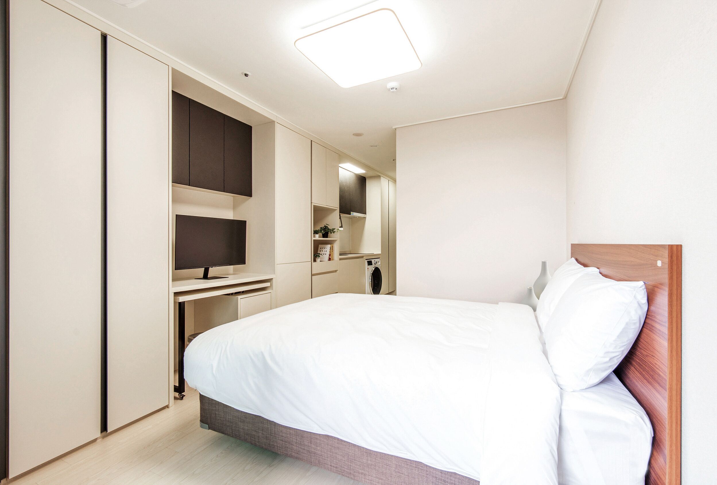Een moderne hotelkamer met een groot bed, een ingebouwde televisie en een kledingkast.