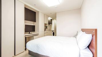 Een moderne hotelkamer met een groot bed, een ingebouwde televisie en een kledingkast.