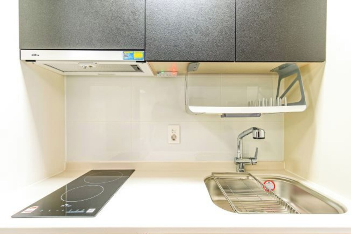 A kitchen with a built-in stove, a sink, and a cabinet above.