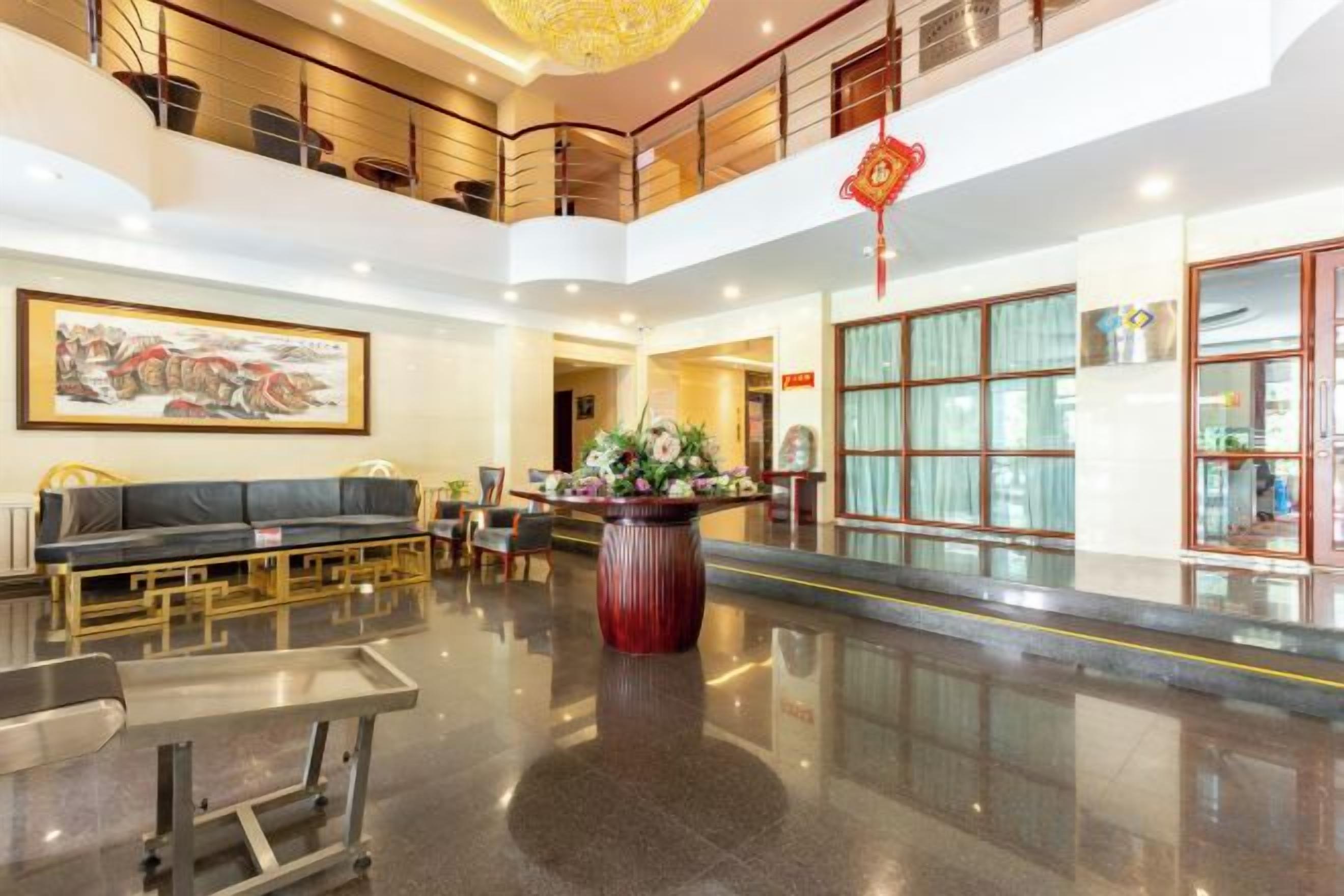 A hotel lobby with a reception desk, seating area, and a large vase of flowers.