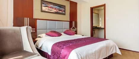 A hotel room with a large bed, a chair, a painting on the wall, and a mirror.