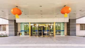 A building entrance with a revolving door and two orange lanterns above.