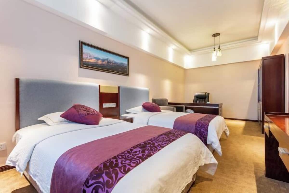 Habitación de hotel con dos camas, un escritorio y una silla.